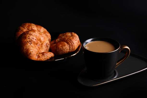 Hot latte coffee with Croissant coffee break isolated in black background