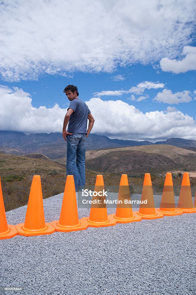 Homem conquistado por uma linha de cones de segurança - Foto de stock de 30 Anos royalty-free