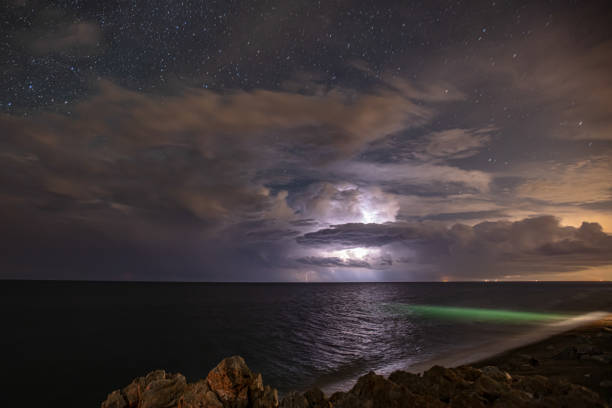 Multiple bright lightning strikes the lake shore during a thunderstorm. Strong electrical storm at night.