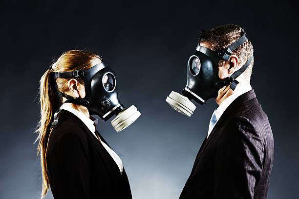 istock Couple in gas masks face off confronting each other 182056512