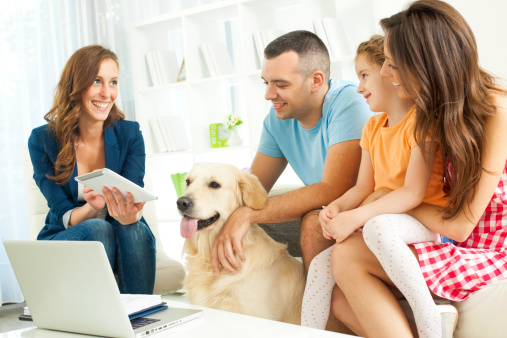 Family with two children Meeting With Financial Advisor presenting new bank offers and investments on digital tablet. Financial Advisor pointing with pen to some new offers. Selective focus to family.