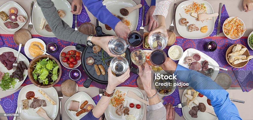 Brindando sobre mesa de jantar com frutos do mar e carnes grelhadas - Foto de stock de Brinde royalty-free