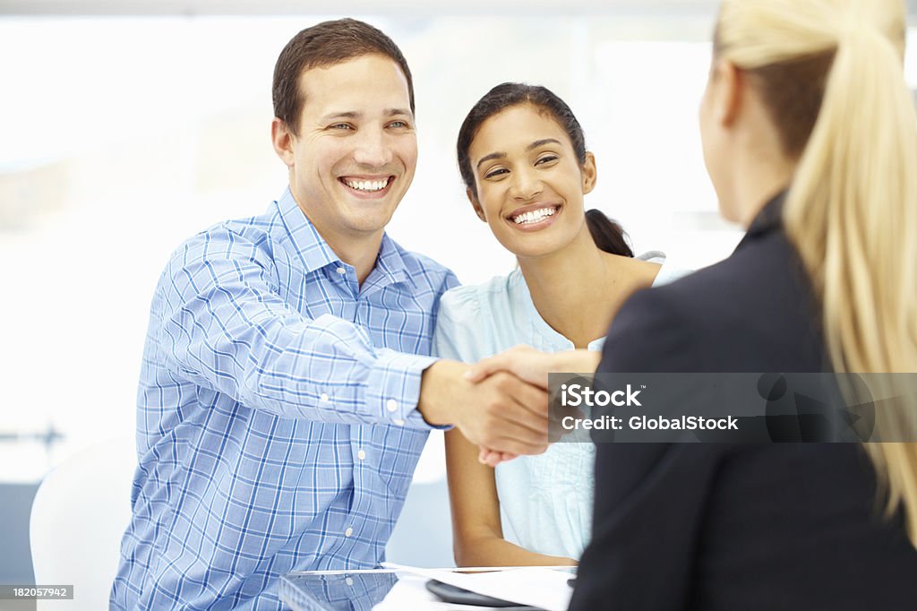 Thanks for all your great advice Smiling young interracial couple shaking hands with a consultant Financial Advisor Stock Photo