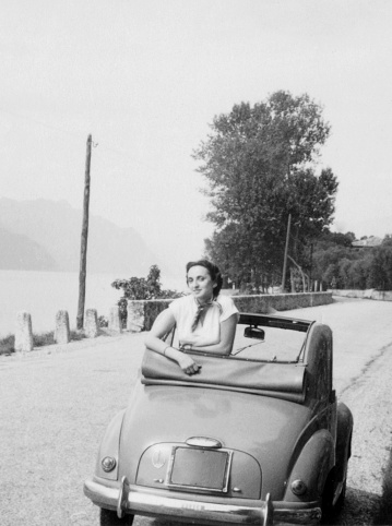 Young woman and vintage car Fiat 500 Topolino in a road. 1952.