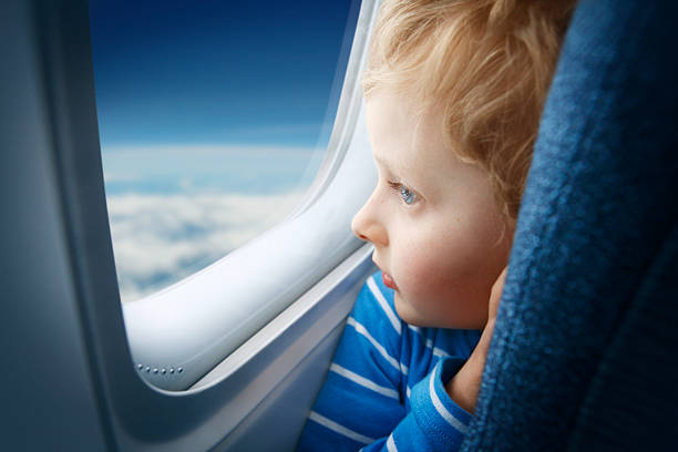 junge beobachten sie den himmel durch das flugzeug-fenster - fensterplatz fahrzeugsitz stock-fotos und bilder