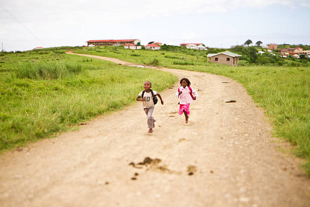 feliz jovem irmão e irmã correndo para a escola em - rural africa - fotografias e filmes do acervo