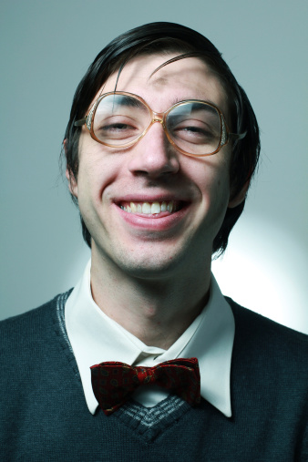Headshot of happy middle aged man wearing bow tie and shirt while standing at isolated grey background. Copy space.