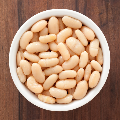 Top view of white bowl full of soaked white beans