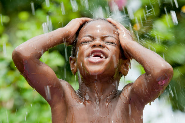 bathing boy is splashing the water in a retro zinc bathtub in summer