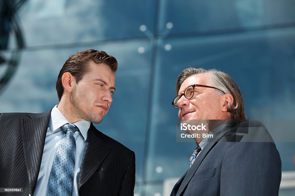 Низкий угол Портрет двух бизнесменов, корпоративные здания на заднем плане - Стоковые фото 25-29 лет роялти-фри