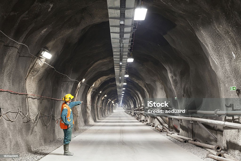 Pointing downward in a tunnel/mine Professional underground workerpointing downward in a tunnel/mine. Mining - Natural Resources Stock Photo
