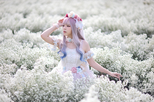 Beautiful young woman with white lolita dress with flowers garden Japanese fashion