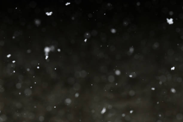 istock Bokeh of white snow on a black background. Snowfall - design element. 1820607540