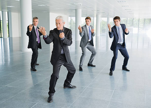 Business Training Full length of multiethnic male business professionals training in T'ai Chi in office lobby fighting stance stock pictures, royalty-free photos & images