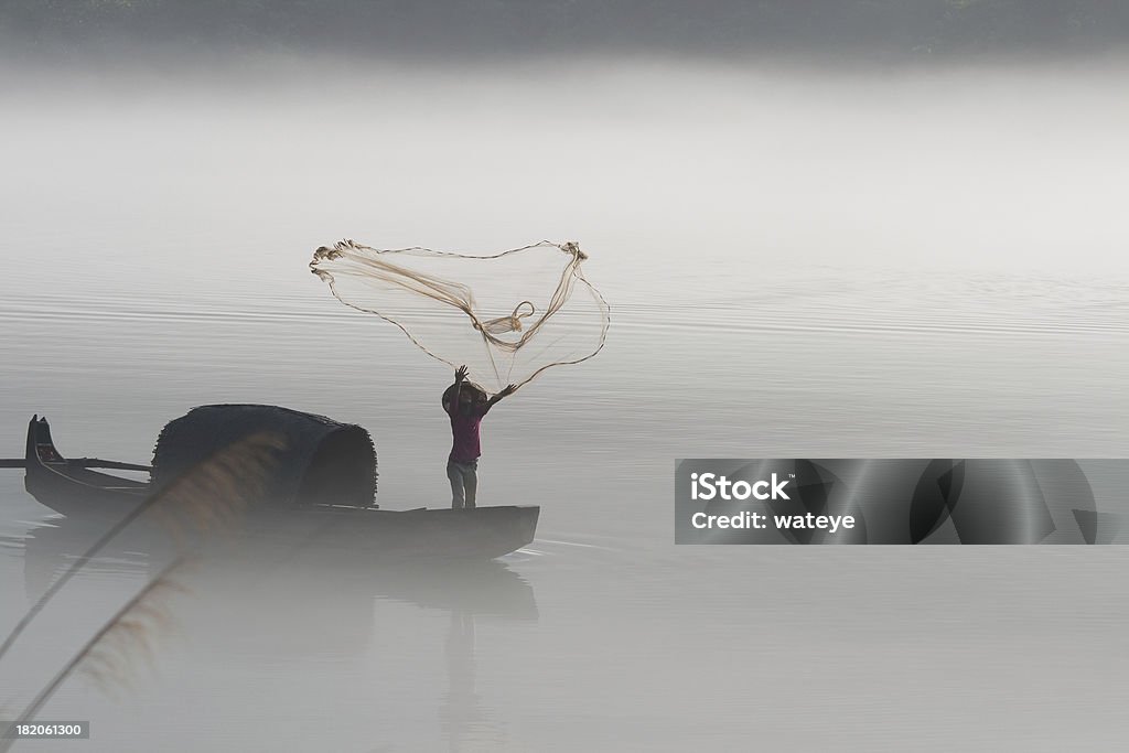 Fisherman casting net on river The fishermen net to fish in the fogSee my collections: Activity Stock Photo