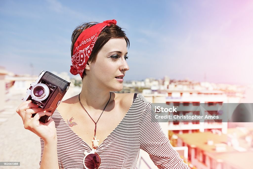 Young Woman with Old-Fashioned Camera Summer fashion shot of a young woman on the roof of a tall building in the south of France posing with an old-fashioned medium format camera with bellows. Its a beautiful sunny day and the image has visible light leak effects. Camera - Photographic Equipment Stock Photo
