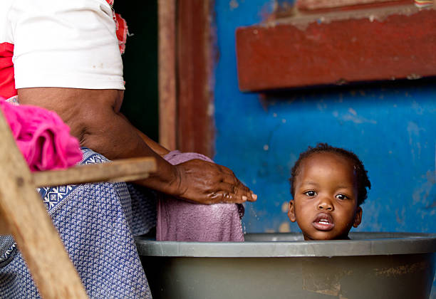 grand-mère donne sa petite-fille un bain dans la campagne de l'afrique du sud - africa south africa child african culture photos et images de collection