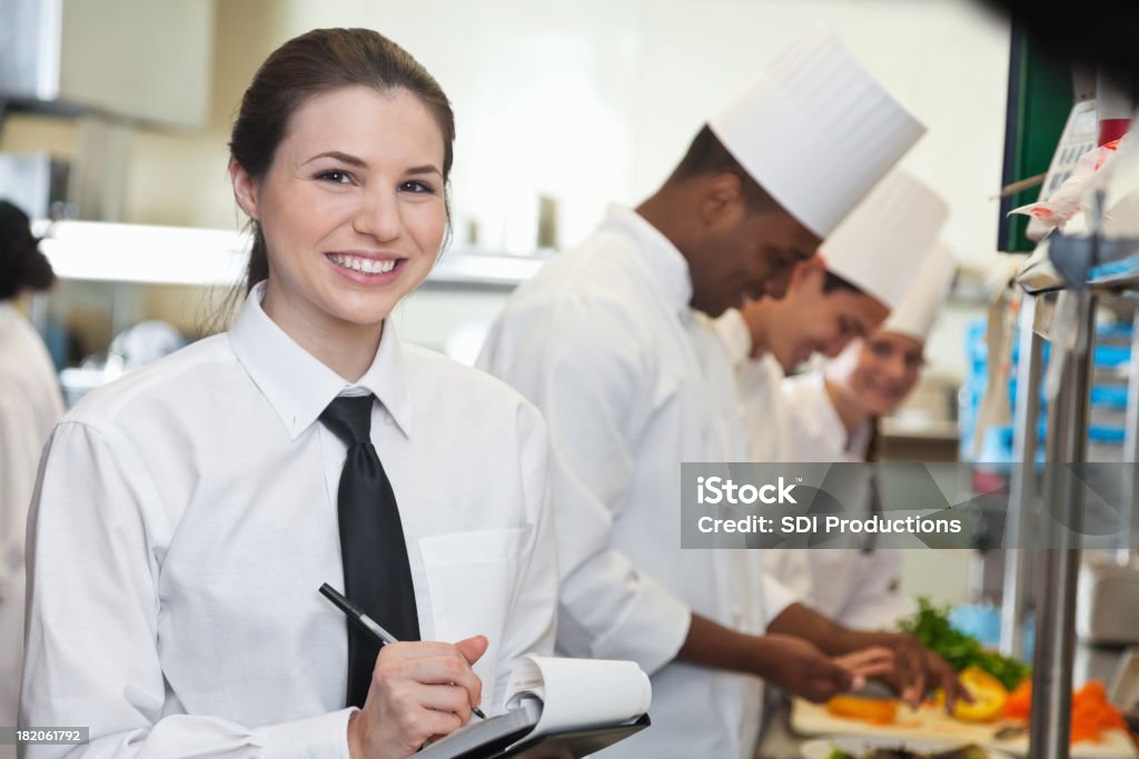 Красивая официантка в ресторане кухня с шеф-поваров, приготовление пищи - Стоковые фото Официантка роялти-фри