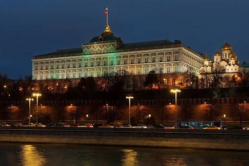 View of the building of the Grand Kremlin Palace and the ensemble of the Kremlin Cathedral Square from the embankment of the Moskva River with night lighting, Moscow, Russia
