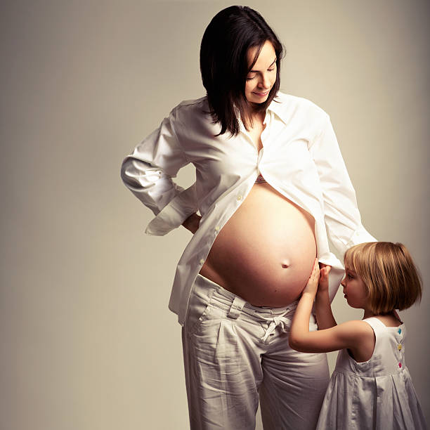 Little girl embracing her pregnant mother in anticipation of baby brother/sister