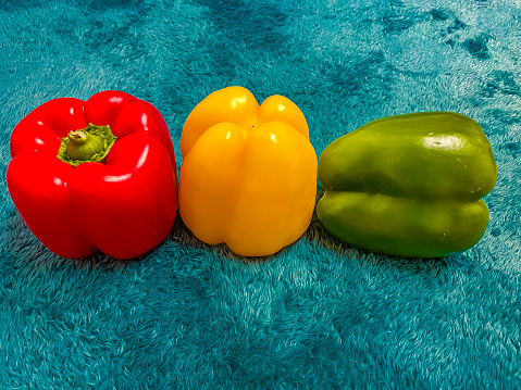 Three bell peppers on a blue background. Red, yellow and green.