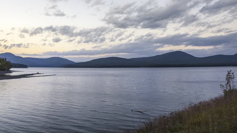 Time lapse of moving clouds over a lake at sunset