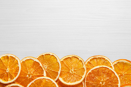 Many dry orange slices on white wooden table, flat lay. Space for text