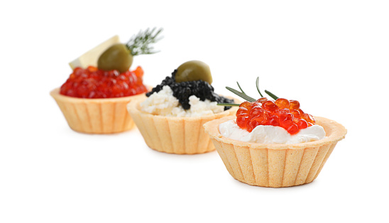 Delicious tartlets with red and black caviar on white background