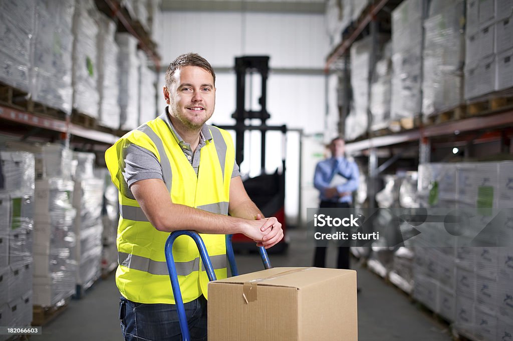 Trabajador almacén utilizando una carretilla industrial - Foto de stock de Carretilla industrial libre de derechos