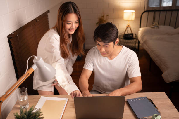istock Happy Asia couple working with computer notebook in night time at home 1820668075
