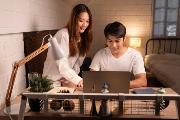 istock Happy Asia couple working with computer notebook in night time at home 1820668148