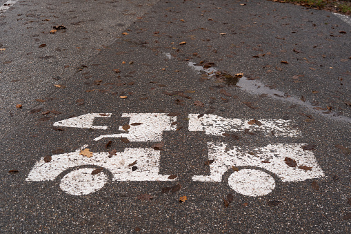camping theme, sign of motor home on wet asphalt of parking space with some old foliage on rainy late autumn season day