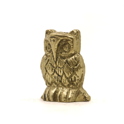 antique bronze owl figurine with old worn out carvings isolated on white background