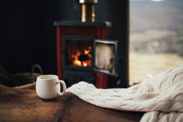 istock White cup with tea with burning fireplace on the background in cozy log cabin. 1820680975