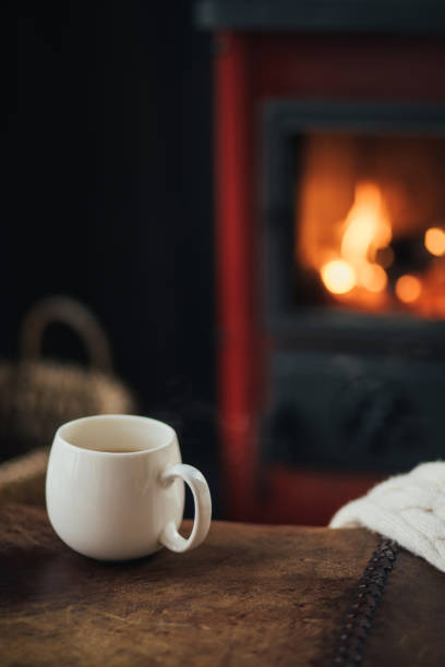 istock White cup with tea with burning fireplace on the background in cozy log cabin. 1820680980
