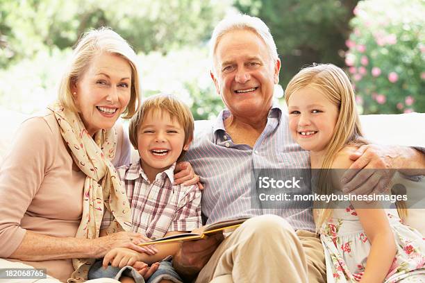 Retrato De Avós Com Netos No Sofá Leitura - Fotografias de stock e mais imagens de Avô - Avô, Avó, Avós e Avôs