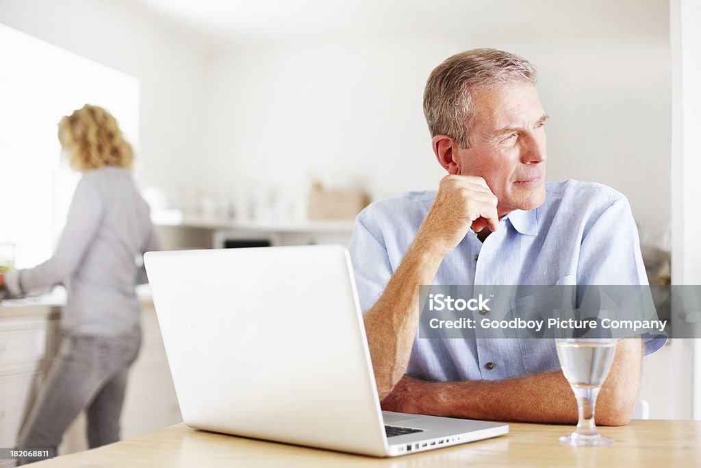 Homem pensativo com laptop enquanto mulher cozinhar na cozinha - Royalty-free Interior de Casa Foto de stock
