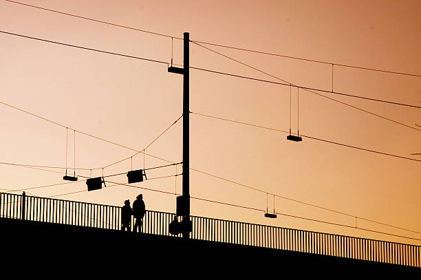 Two pedestrians are walking on a bridge