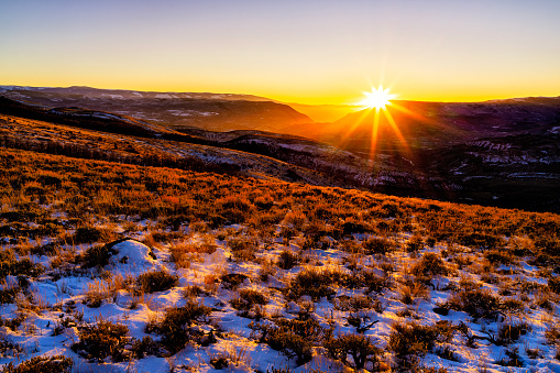 Scenic Sunset Early Winter Mountains Looking West - Layers and layers of mountains, canyons and valleys in scenic landscape image captured during autumn/early winter warm solstice light. Sun star in sky as sun goes behind mountain ridge.