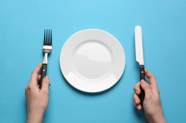 istock Woman with empty plate and cutlery on turquoise background, top view 1820706862