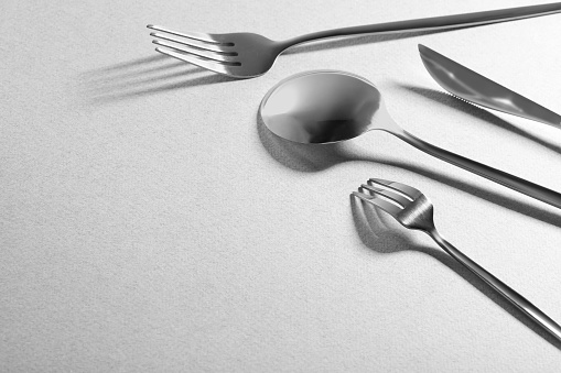 Forks, knife and spoon on grey background, space for text. Stylish cutlery set
