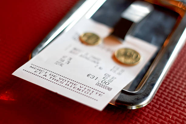 Tip left on a restaurant check European (french) restaurant check with few tip coins left on it. Red paper napkin background, selective focus french currency stock pictures, royalty-free photos & images