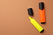 Bright color markers on pale orange background, flat lay. Space for text