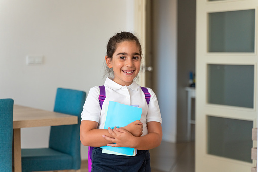 The little girl happily smiles at the camera after completing her preparations for the first day of school