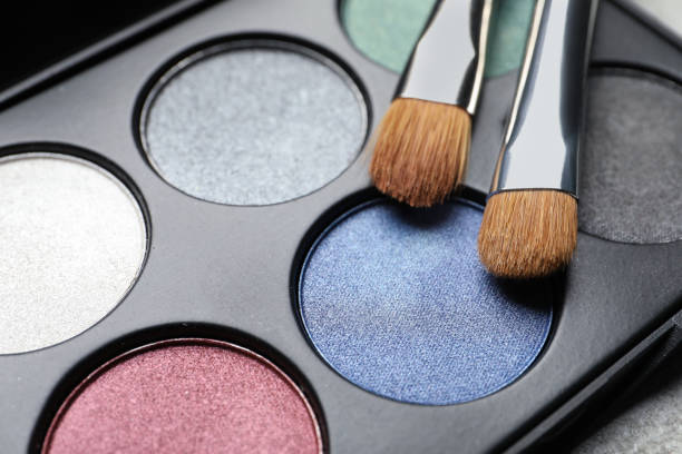 istock Beautiful eye shadow palette and brushes on grey table, closeup 1820755752