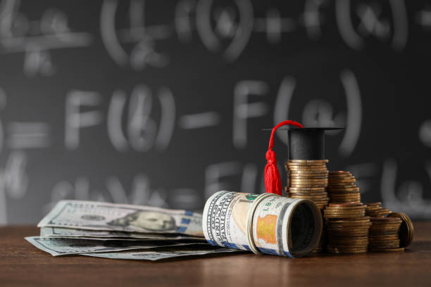 istock Scholarship concept. Coins, dollar banknotes and graduation cap on wooden table 1820759721