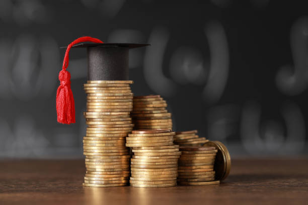 istock Scholarship concept. Coins and graduation cap on wooden table 1820760619