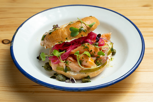 Closeup of smoked salmon bagel sandwich on wooden board