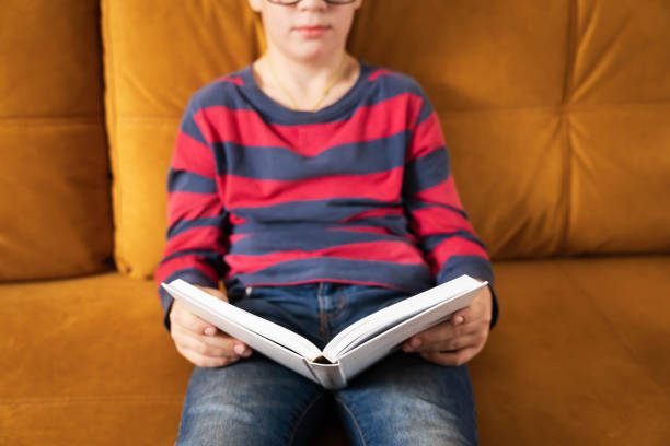 istock Young Curious Boy with Glasses Delving into a Book on the Couch 1820768305