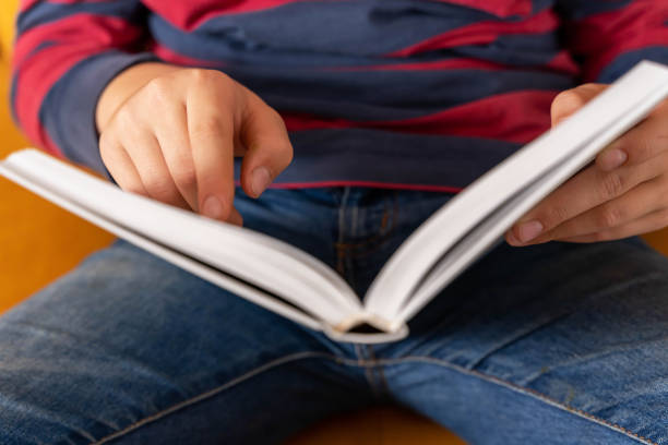 istock Inquisitive young boy reading a book on the couch with unreadable face 1820768307